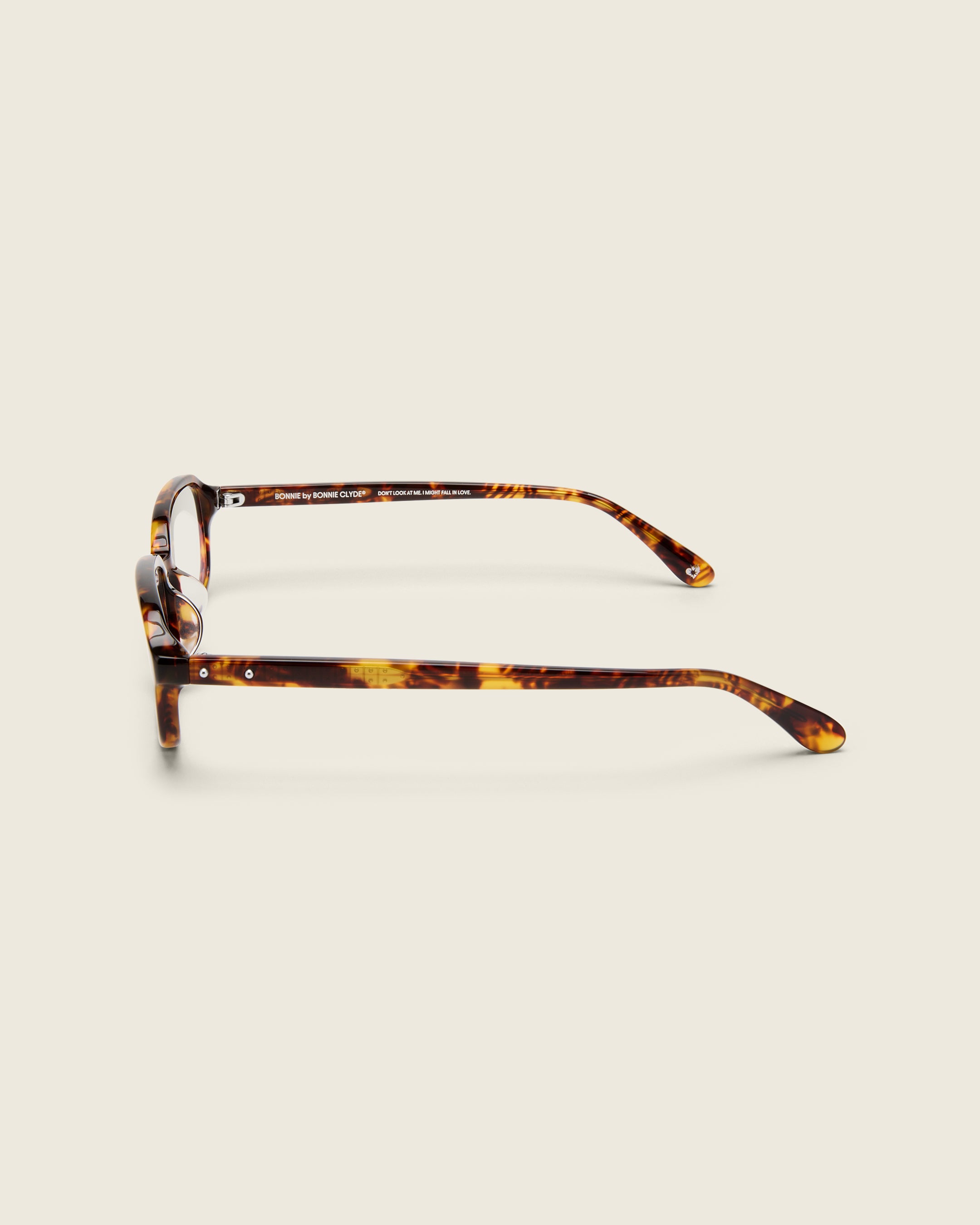 Rectangular tortoise acetate frames with softened corners and a low-profile bridge on a beige background. Side view.