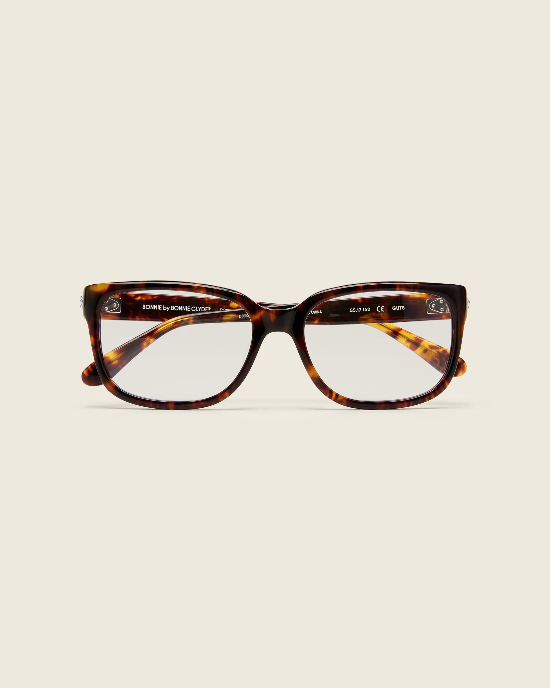 Bold, square-shaped tortoise acetate frames on a beige background. Face view. Mirrored metal bead detail on arm temples.
