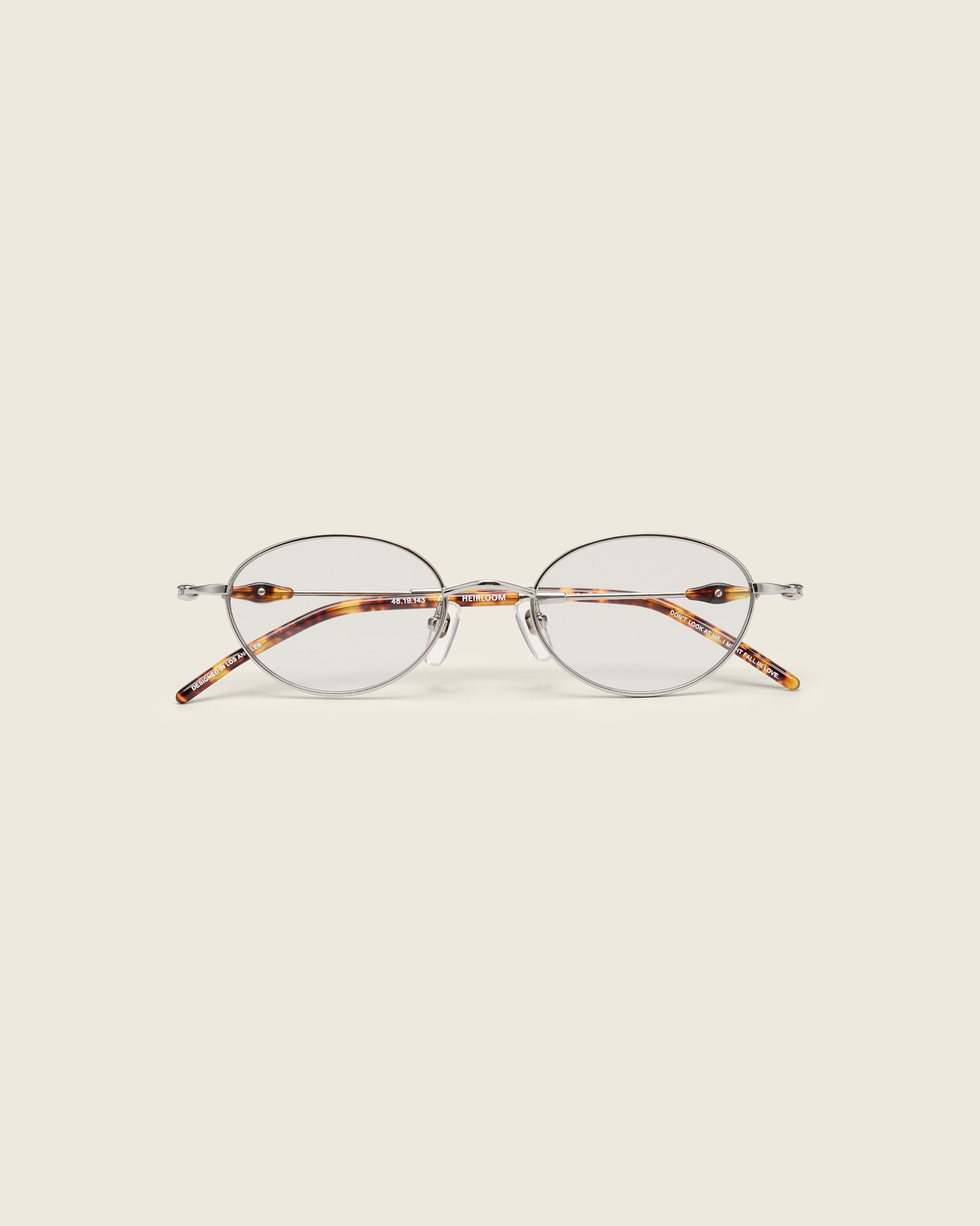 Slim, oval silver titanium frames with adjustable nose pads and lightweight acetate arm temple. Face view.