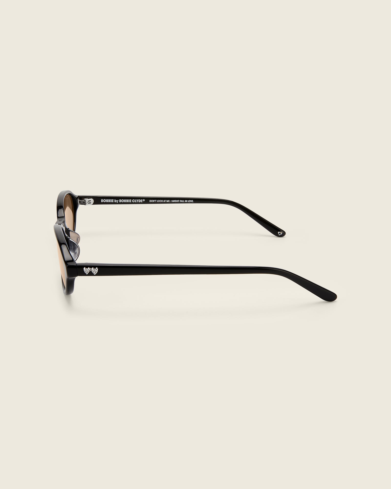 Bonnie Clyde Baby oval sunglasses in black acetate with brown lenses and double heart detailing on the arms, side view