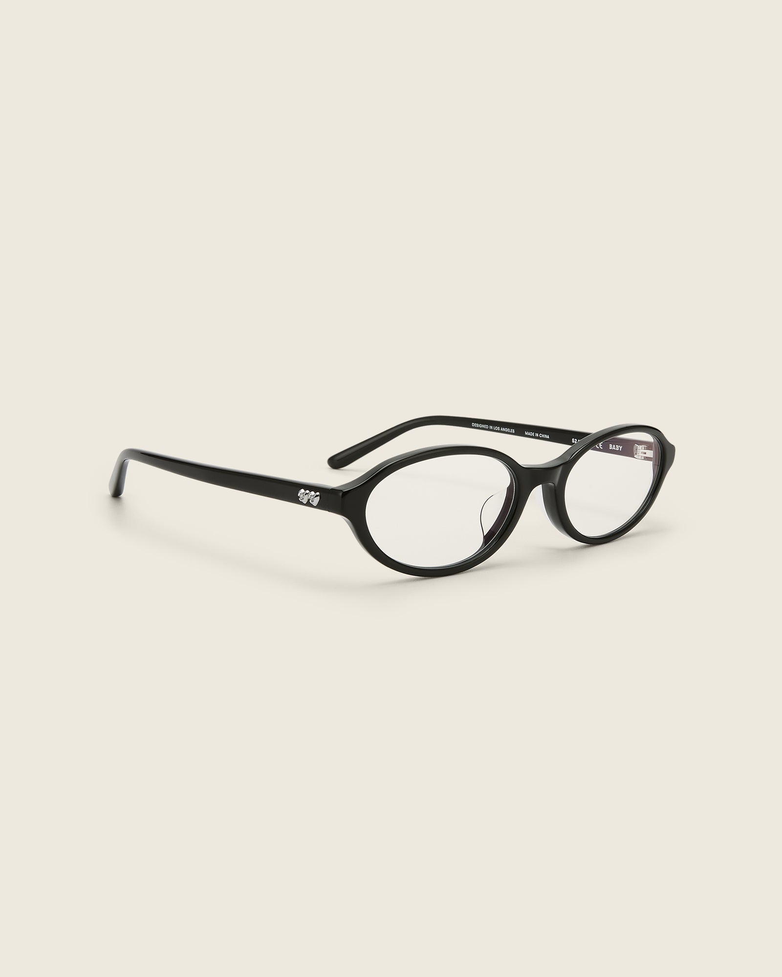 Bonnie Clyde Baby oval optical in black acetate with clear lenses and double heart detailing on the arms, quarter view