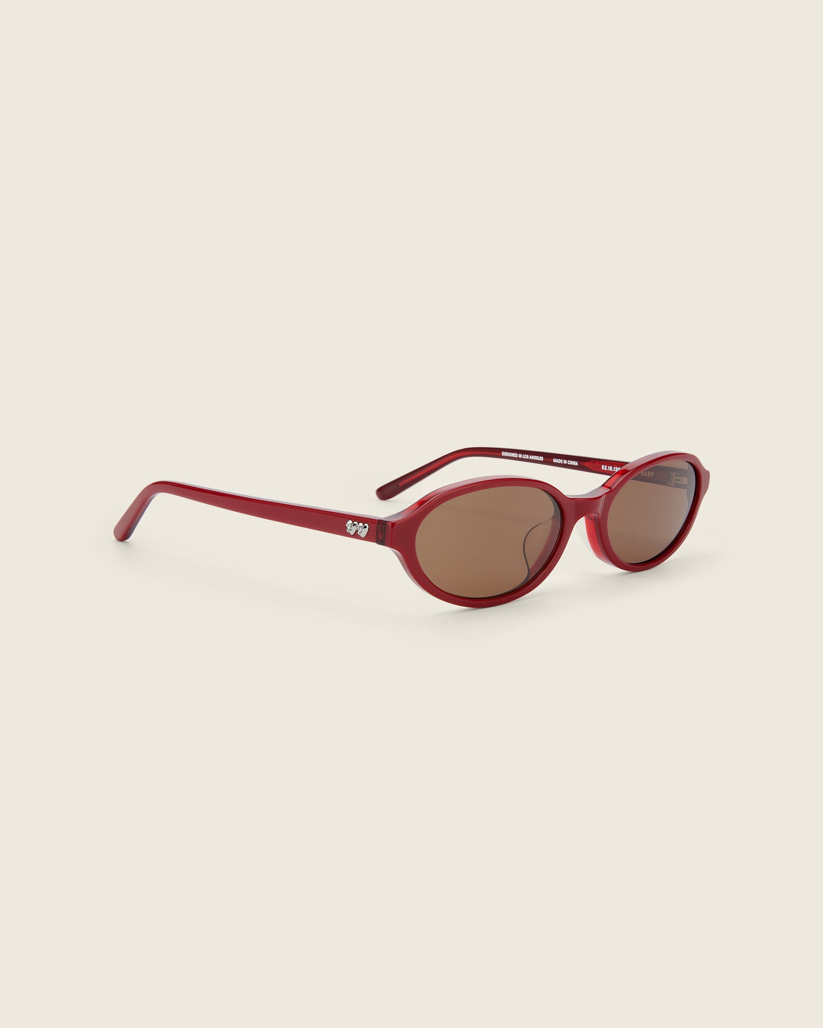 Bonnie Clyde red oval-shaped acetate sunglasses with brown lenses and double heart detailing on the arms, three-quarter view