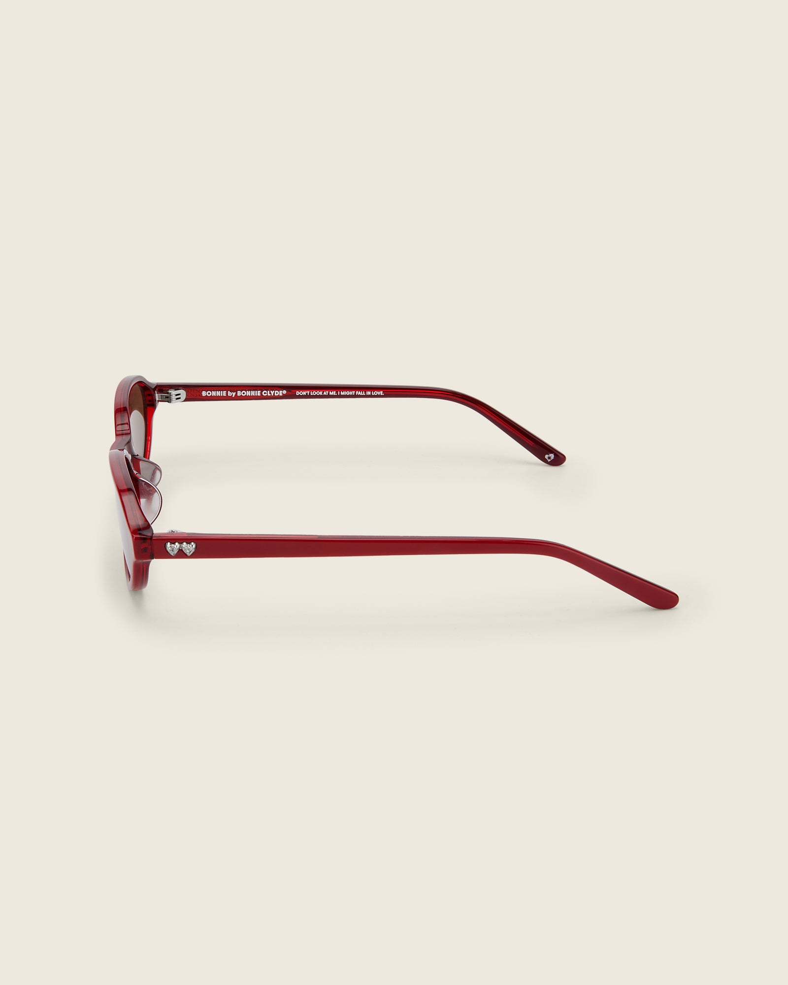 Bonnie Clyde red oval-shaped acetate sunglasses with brown lenses and double heart detailing on the arms, side view