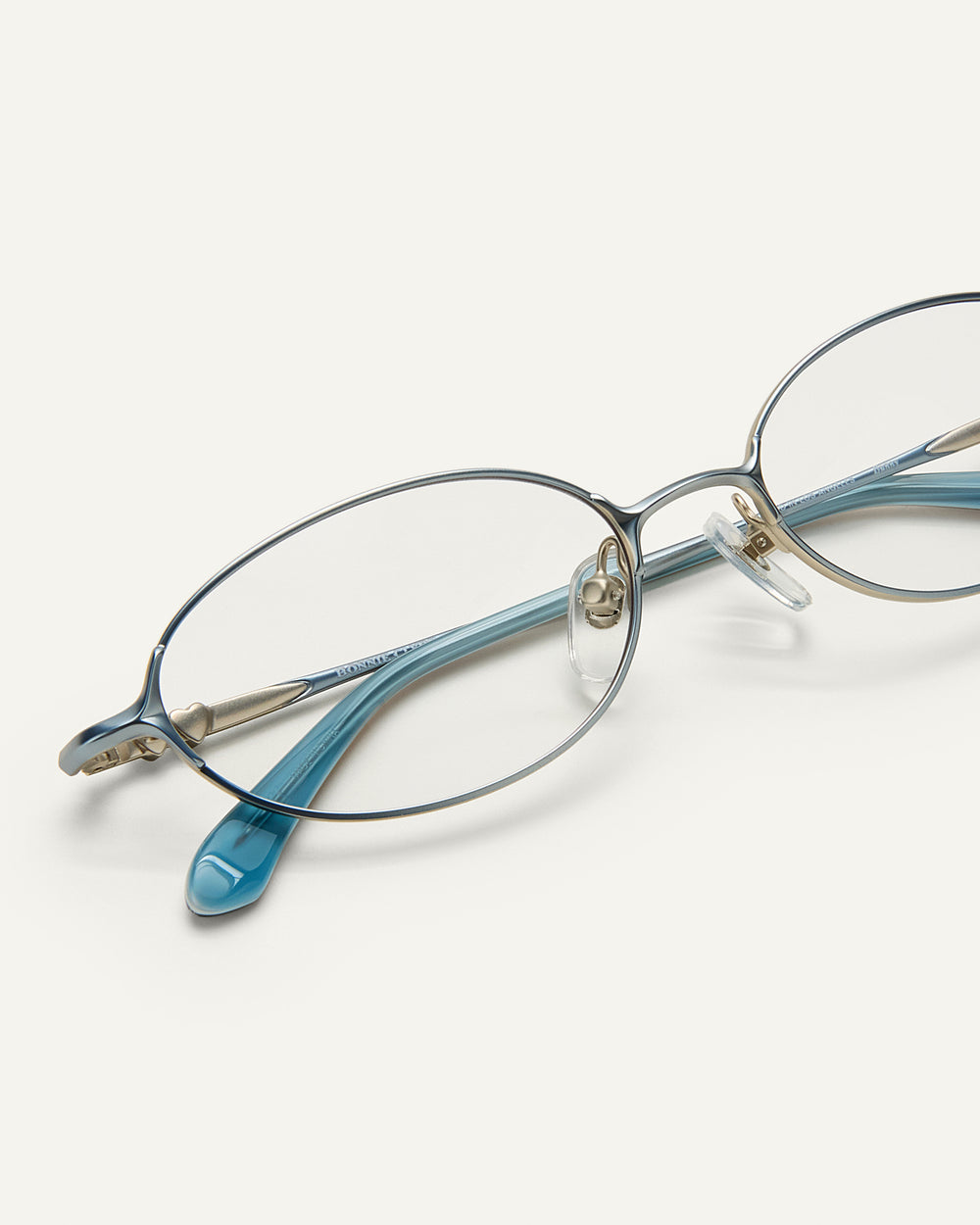 Close Up shot of Bonnie Clyde Bunny eyeglasses in titanium silver with teal acetate and clear lenses. 