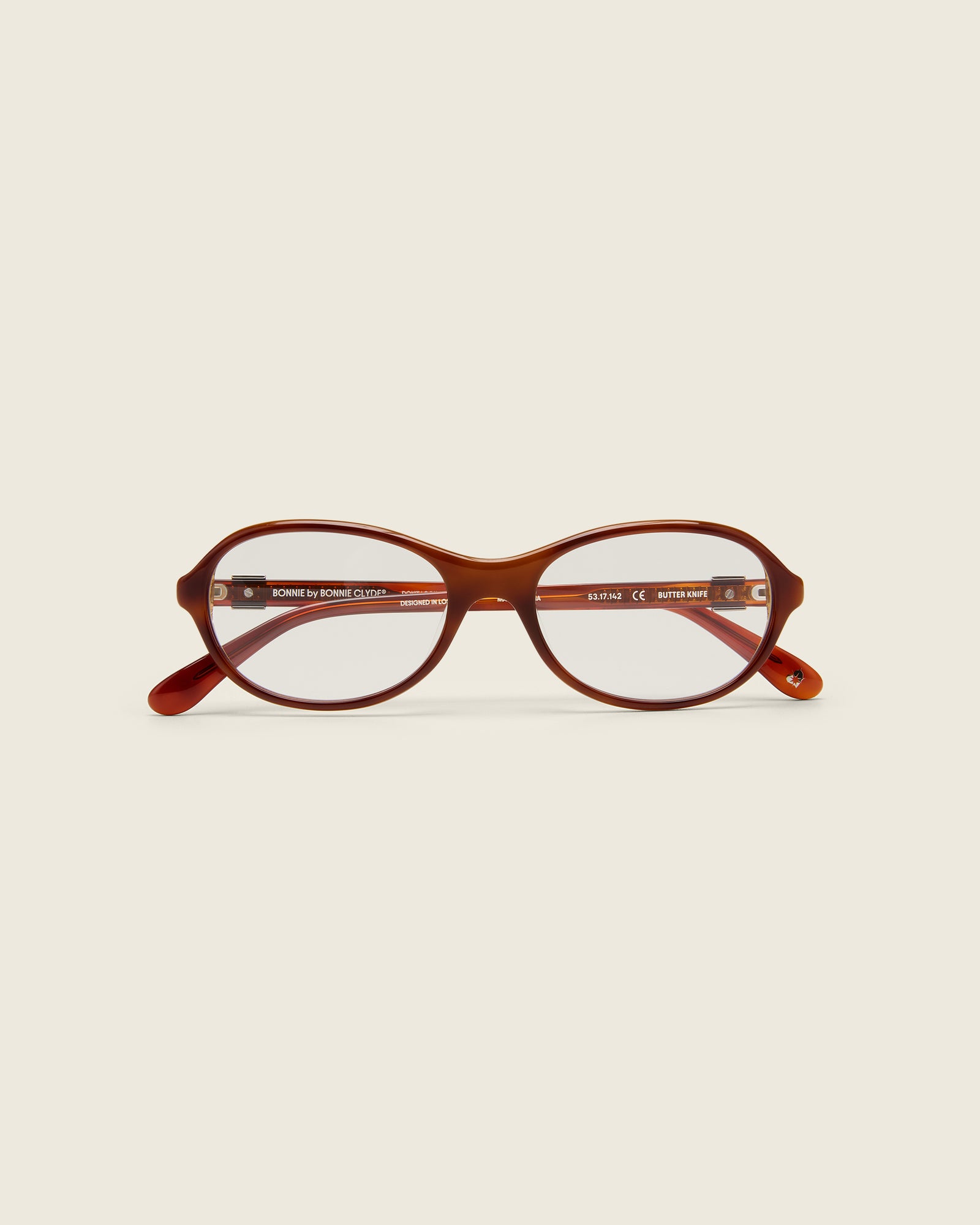 Rounded brown tortoise acetate frames. Features raised browline curvature on a beige background. Face view.