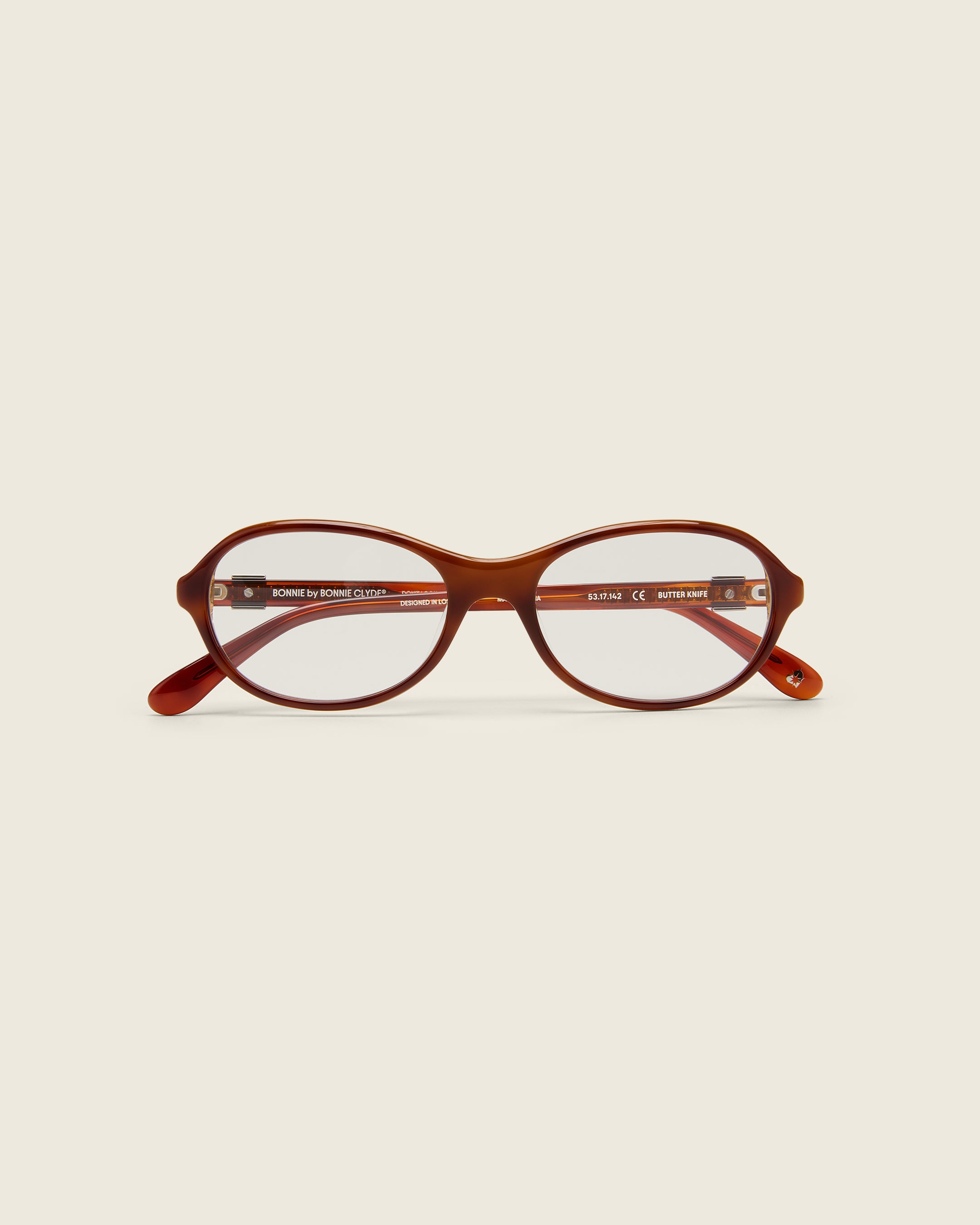 Rounded brown tortoise acetate frames. Features raised browline curvature on a beige background. Face view.