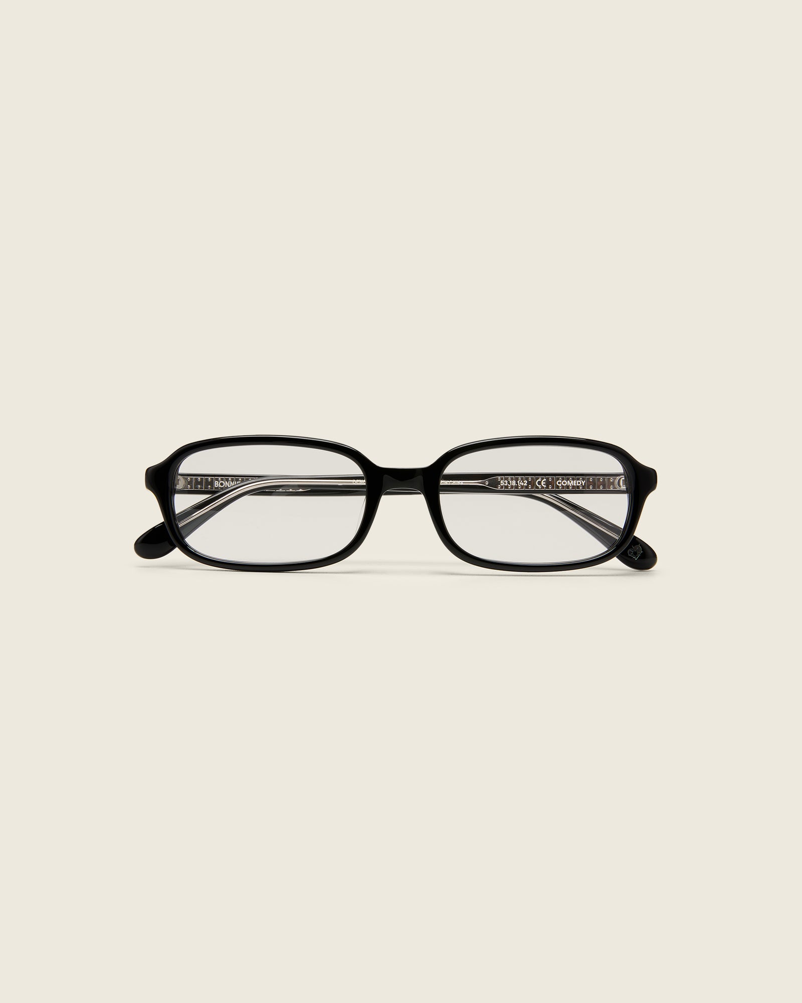 Black rectangular acetate frames with softened corners and a low-profile bridge on a beige background. Face view.