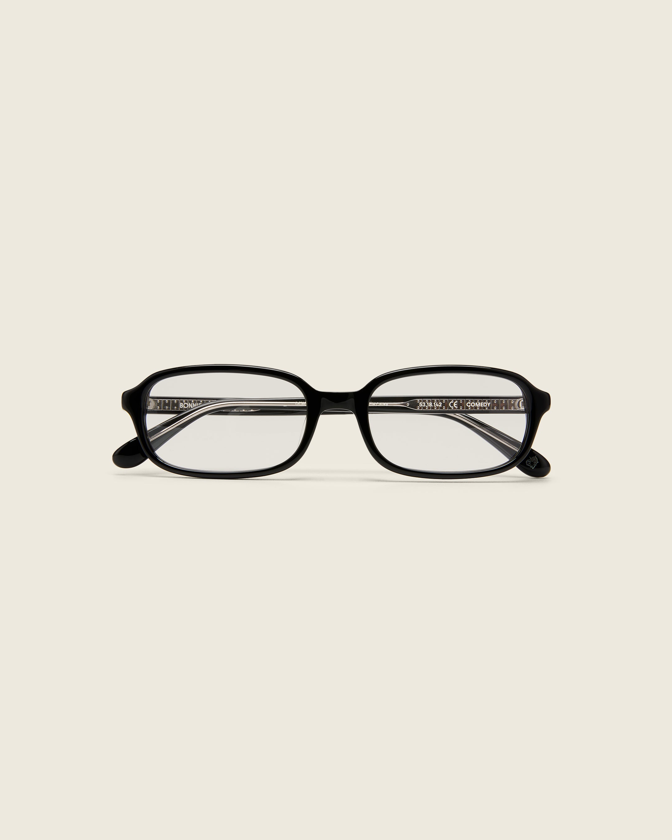 Black rectangular acetate frames with softened corners and a low-profile bridge on a beige background. Face view.