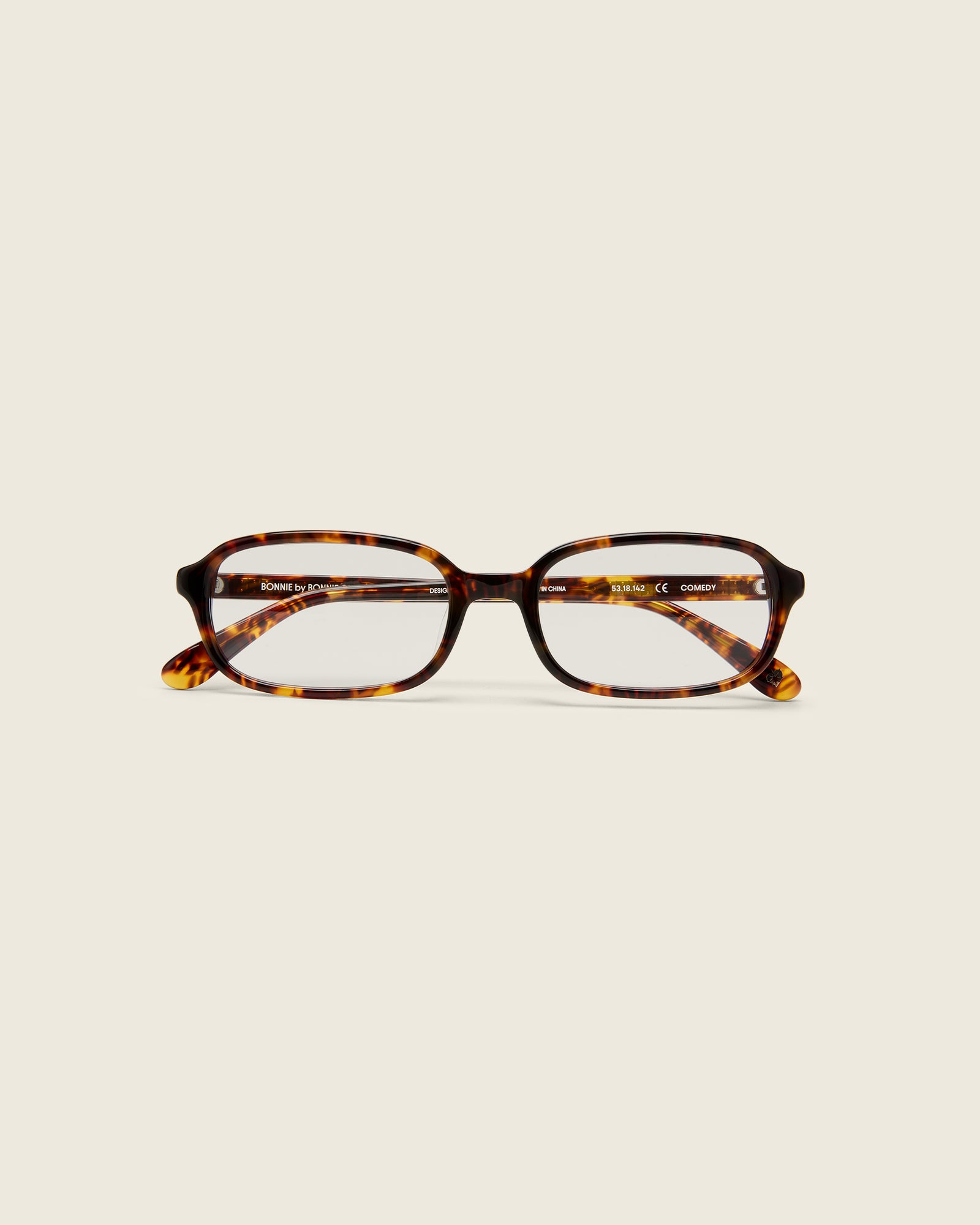Rectangular tortoise acetate frames with softened corners and a low-profile bridge on a beige background. Face view.