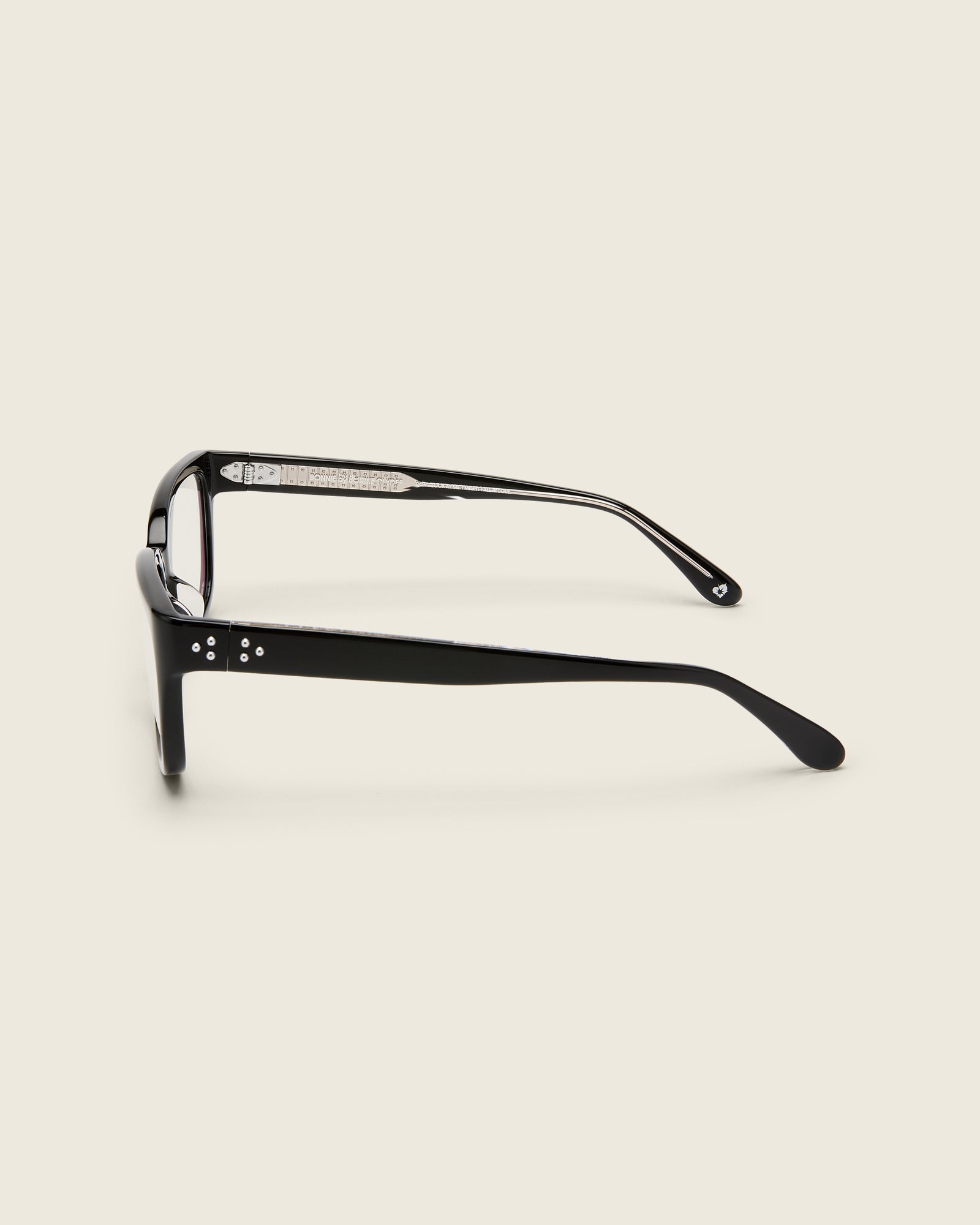 Bold, square-shaped black acetate frames on a beige background. Side view. Mirrored metal bead detail on arm temples.