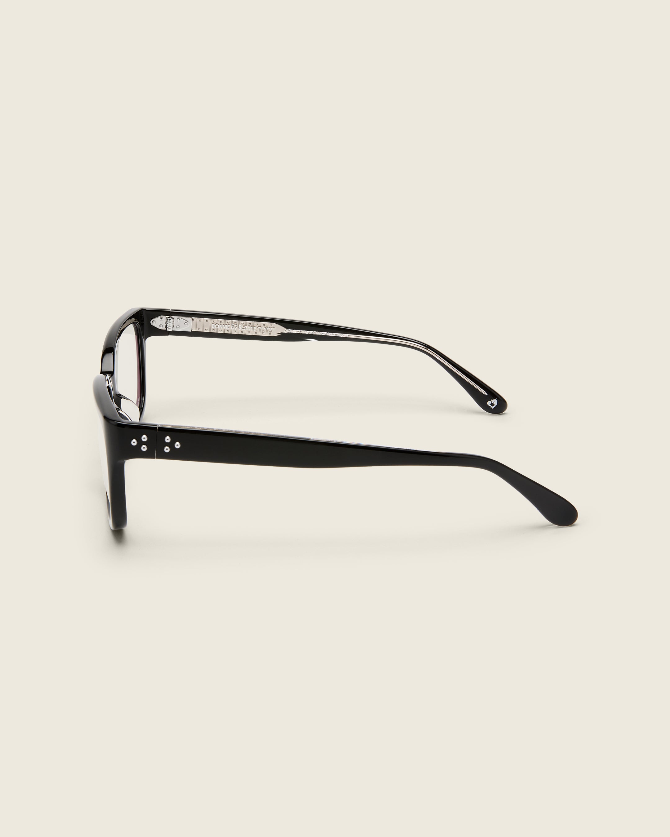 Bold, square-shaped black acetate frames on a beige background. Side view. Mirrored metal bead detail on arm temples.