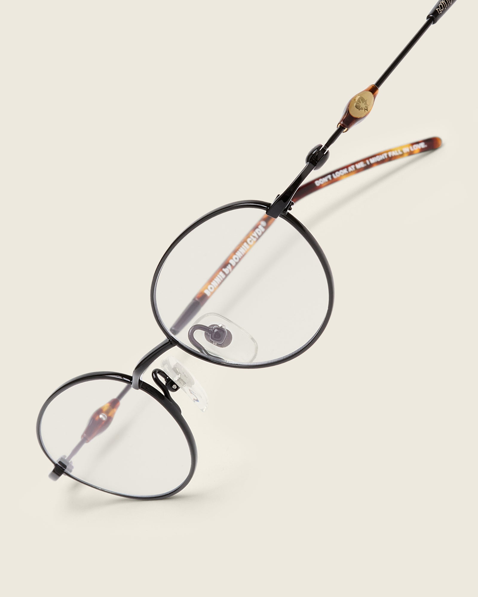 Slim, oval black titanium frames with adjustable nose pads and lightweight acetate arm temple. Detail view.