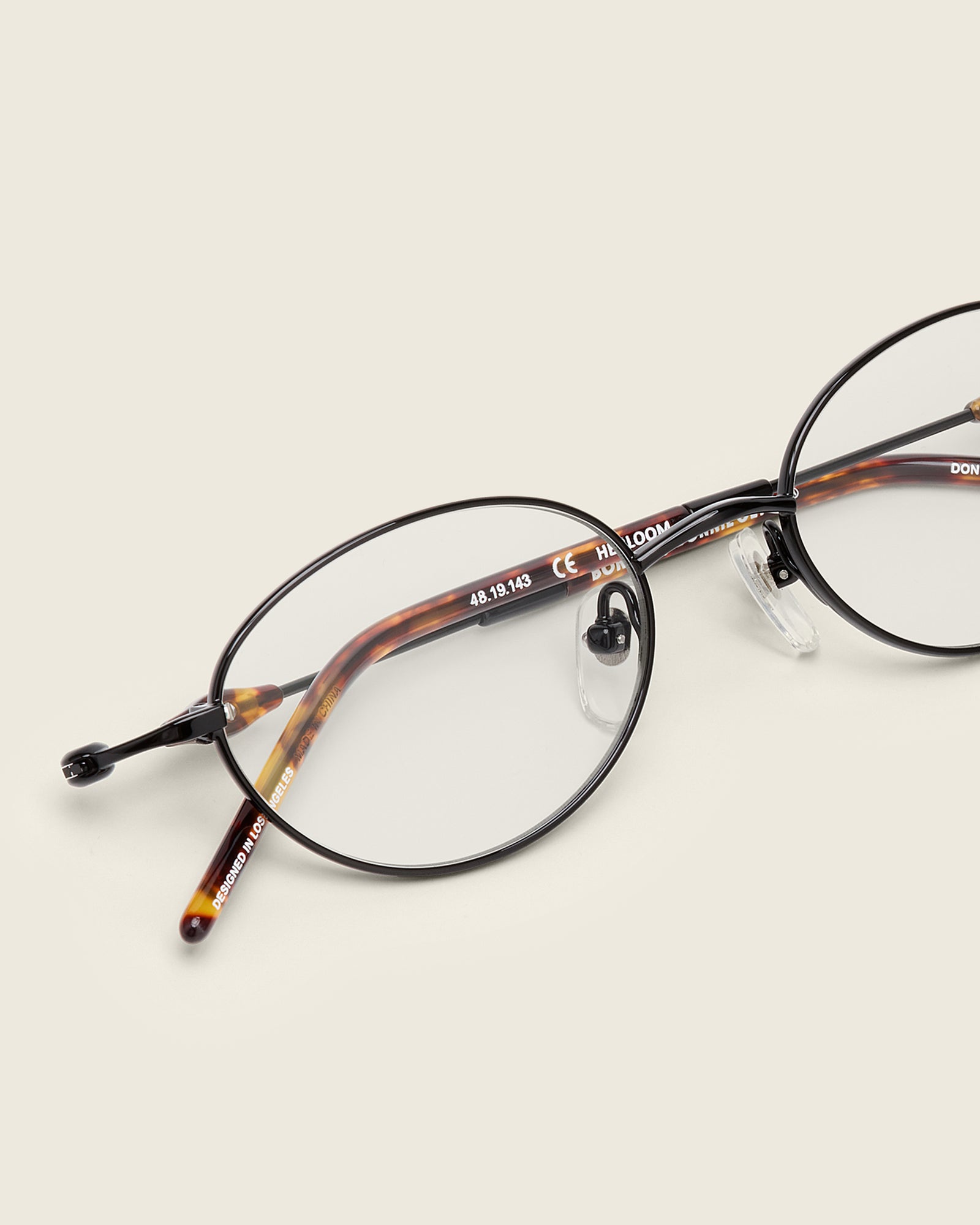 Slim, oval black titanium frames with adjustable nose pads and lightweight acetate arm temple. Detail view.