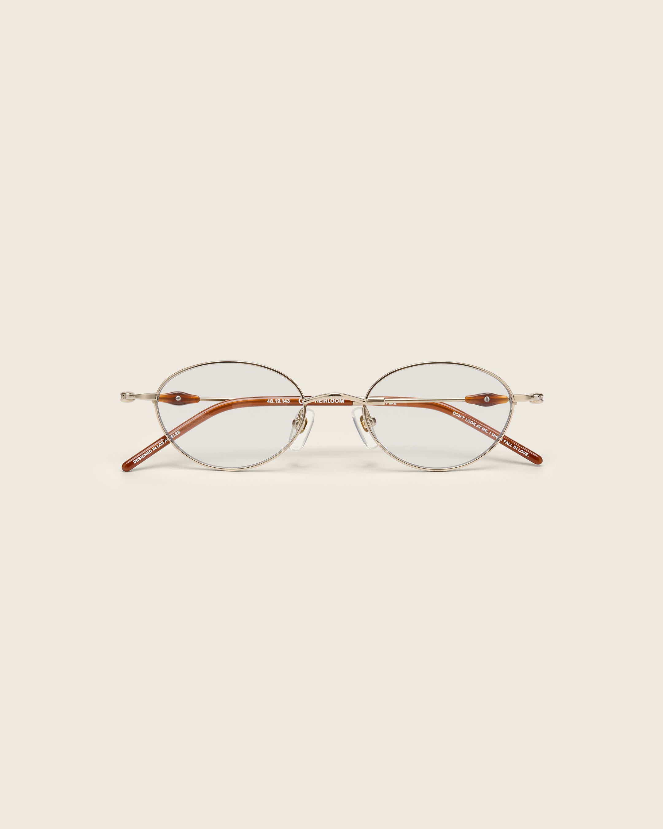 Slim, oval gold titanium frames with adjustable nose pads and lightweight acetate arm temple. Face view.