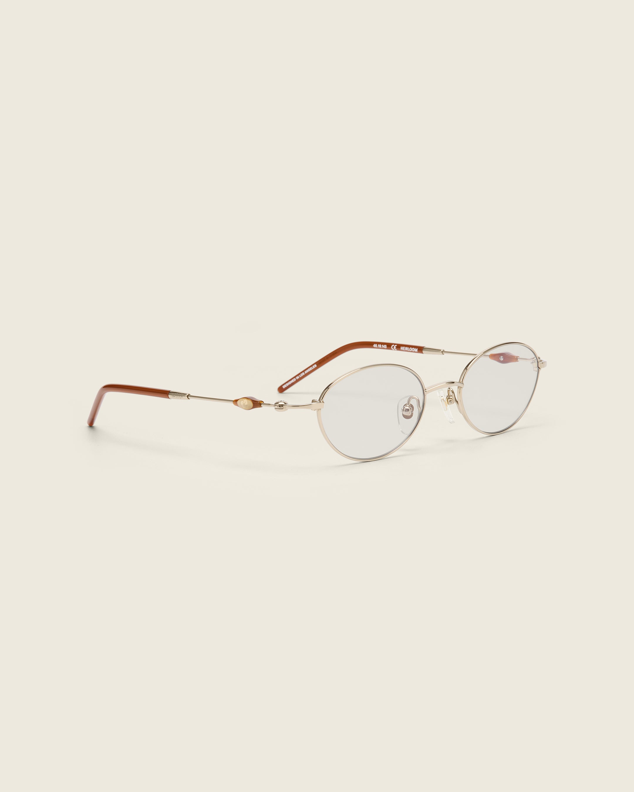 Slim, oval gold titanium frames with adjustable nose pads and lightweight acetate arm temple. Quarter view.