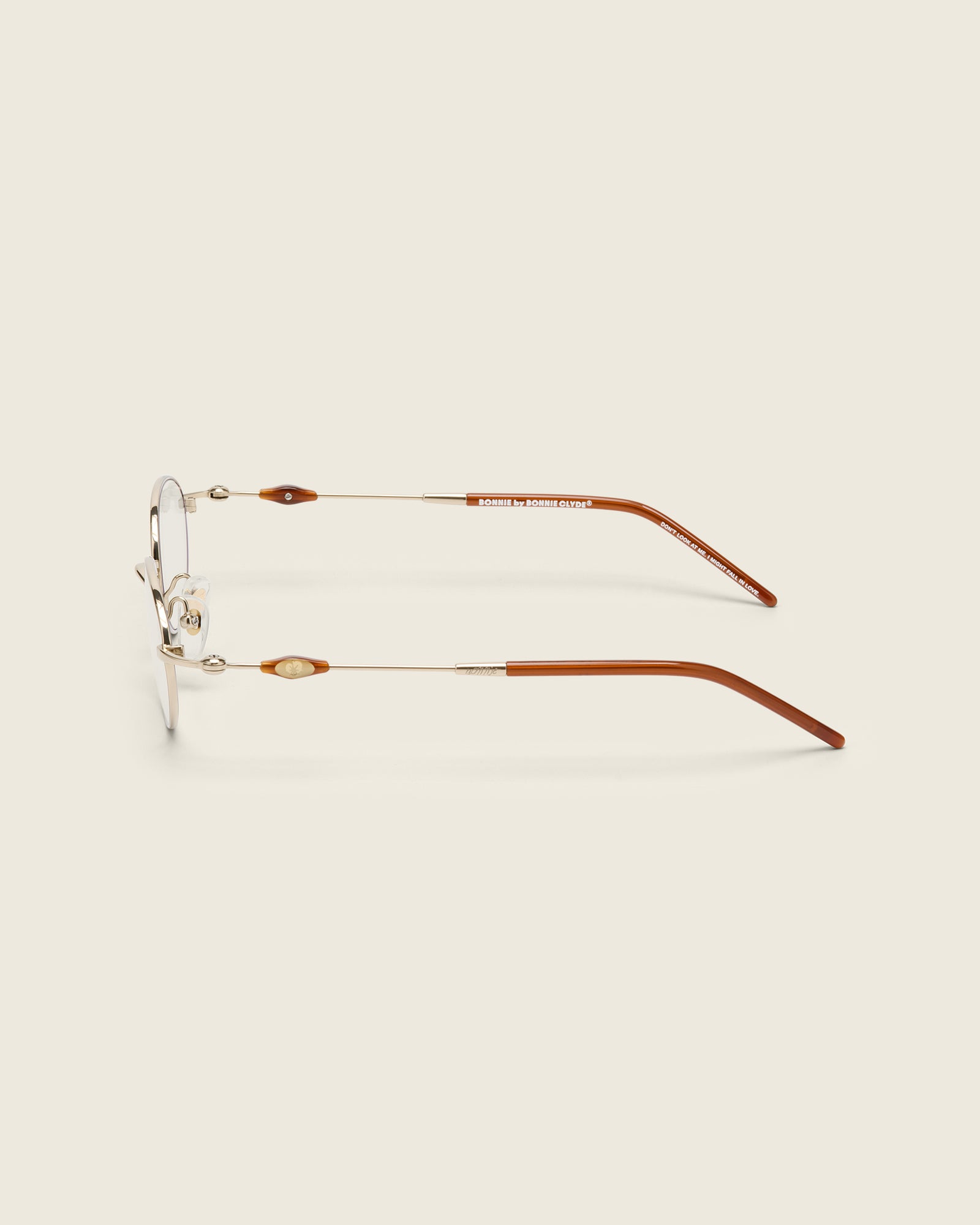 Slim, oval gold titanium frames with adjustable nose pads and lightweight acetate arm temple. Side view.