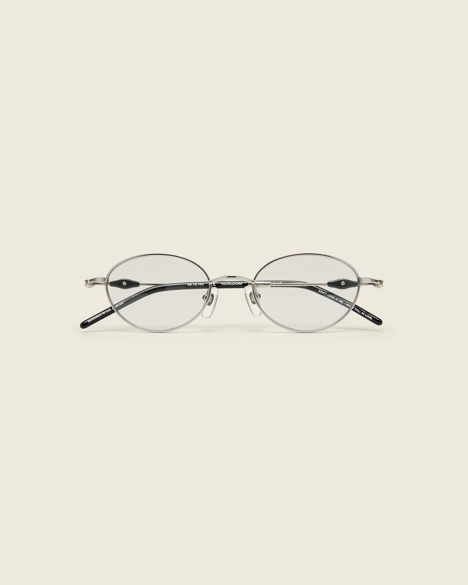 Slim, oval silver titanium frames with adjustable nose pads and lightweight acetate arm temple. Face view.