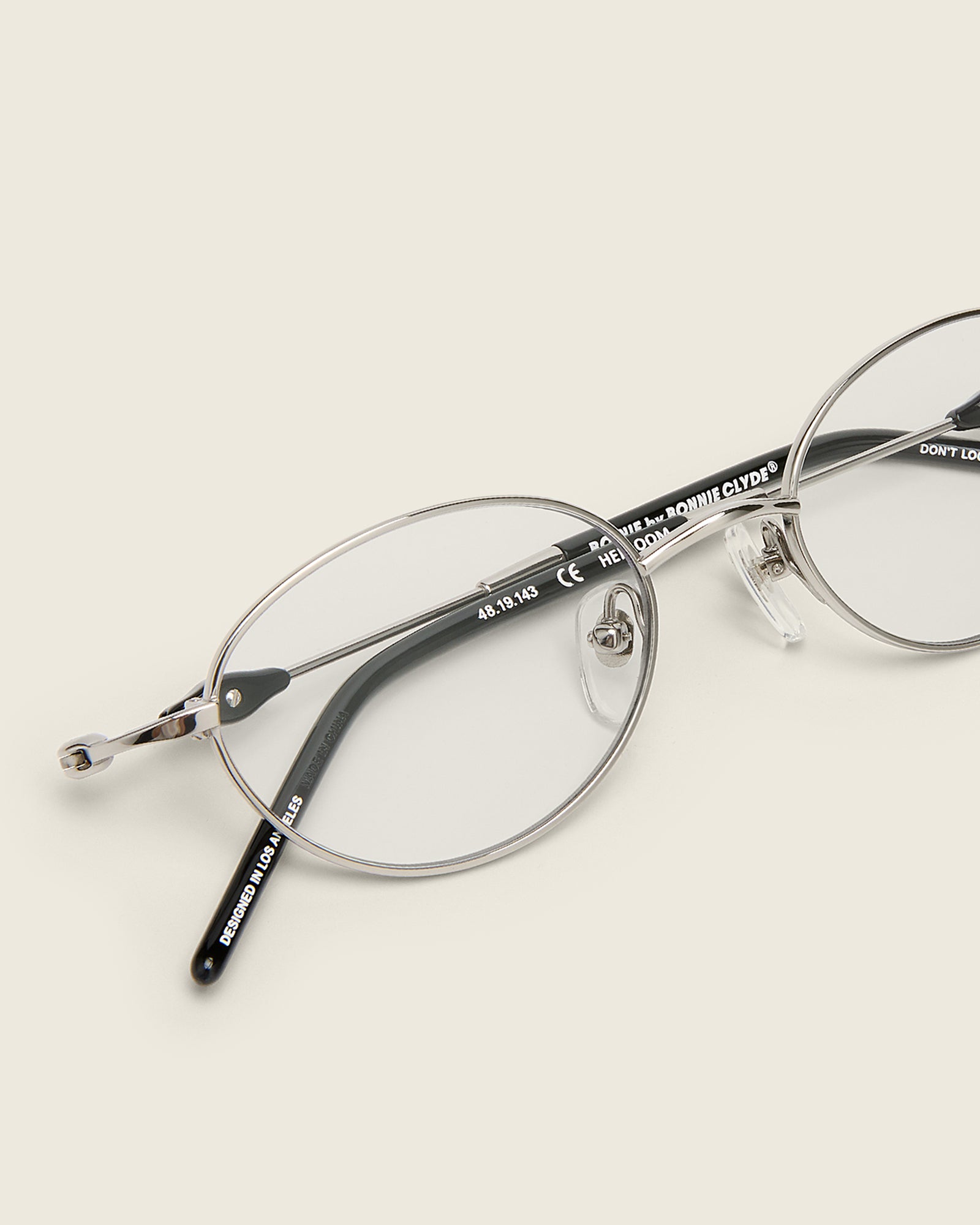 Slim, oval silver titanium frames with adjustable nose pads and acetate arm temple. Detail view.