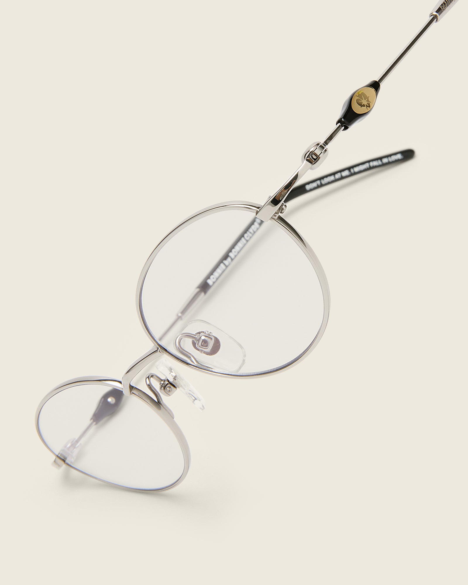 Slim, oval silver titanium frames with adjustable nose pads and acetate arm temple. Detail view.