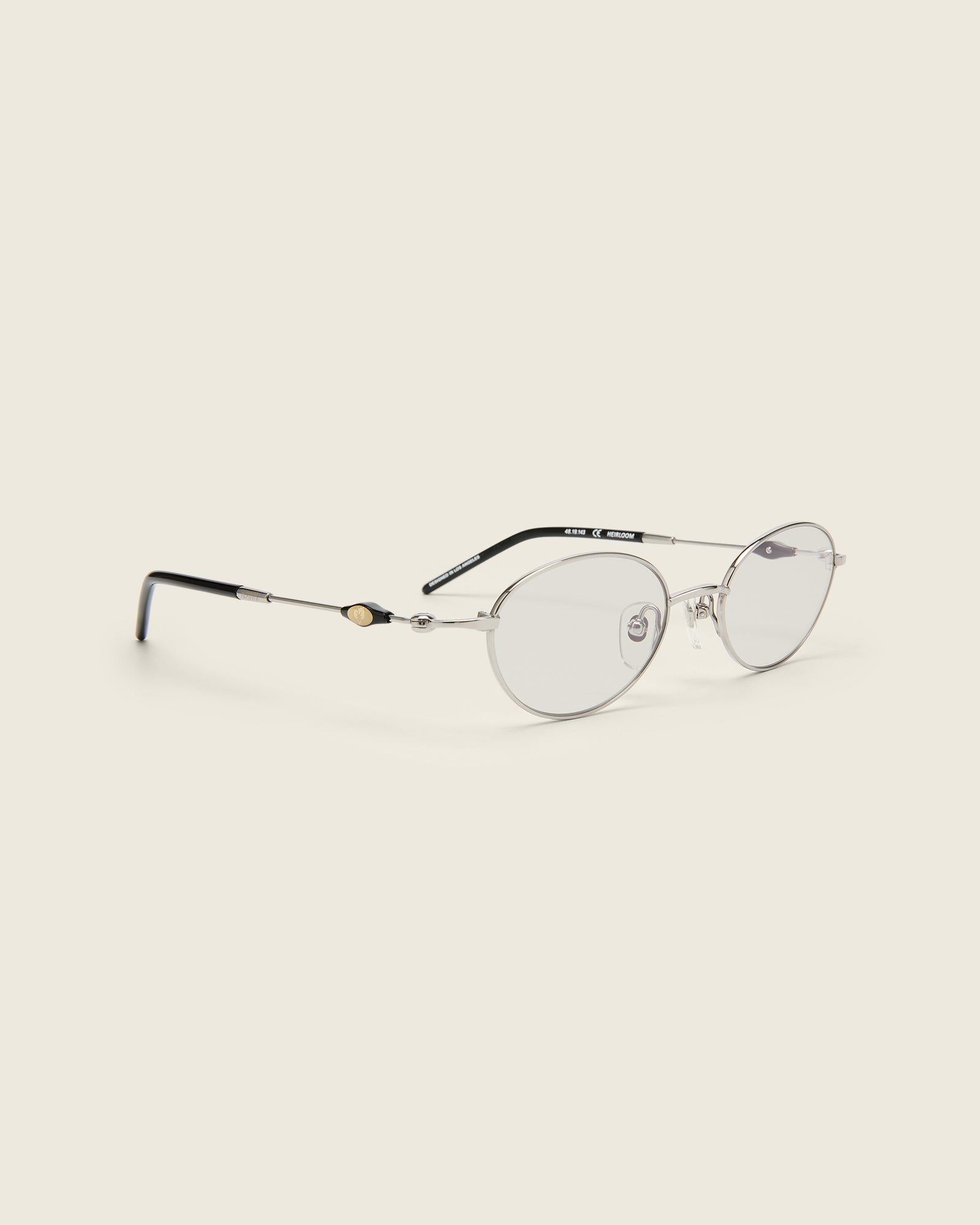 Slim, oval silver titanium frames with adjustable nose pads and acetate arm temple. Quarter view.