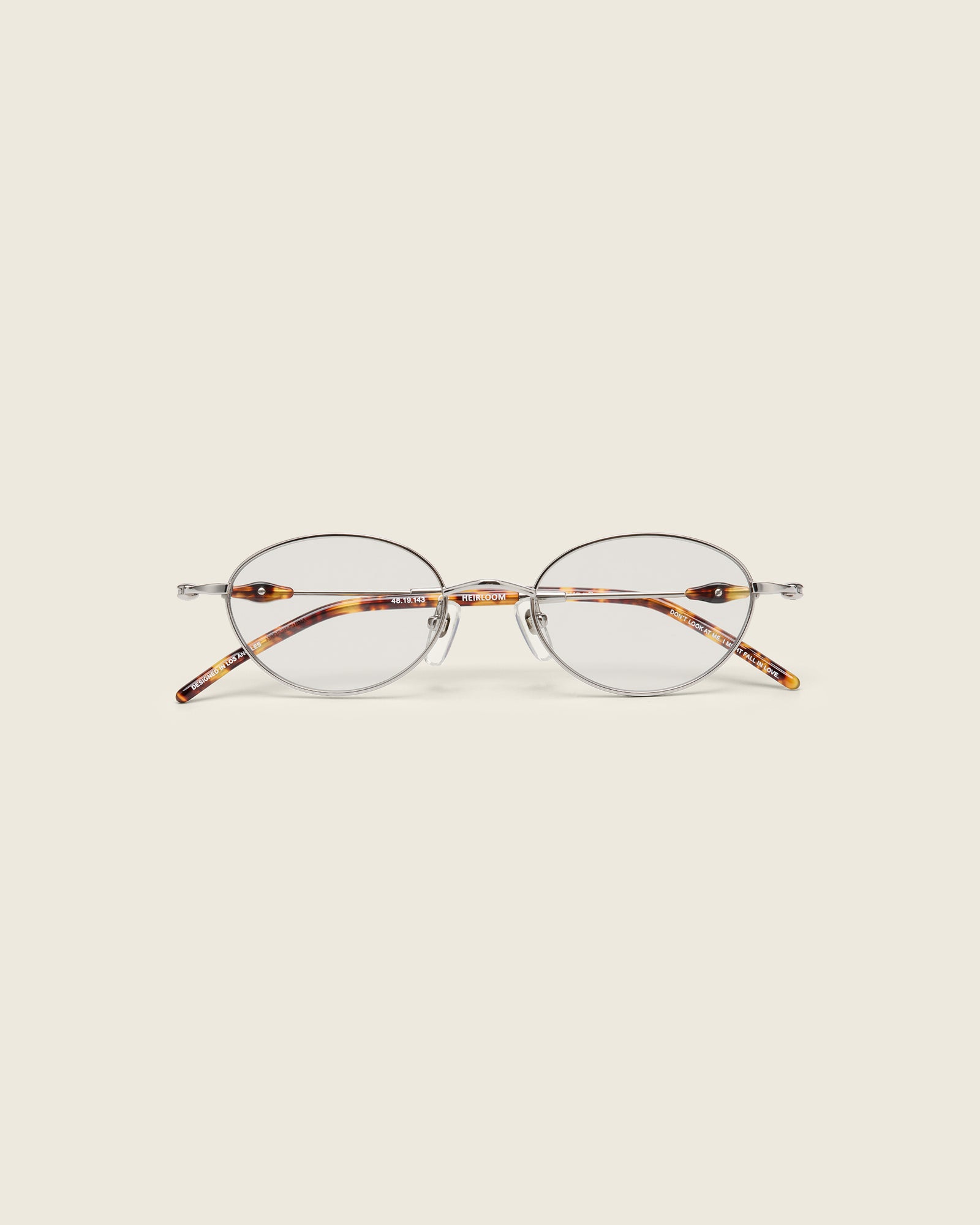 Slim, oval silver titanium frames with adjustable nose pads and lightweight acetate arm temple. Face view.
