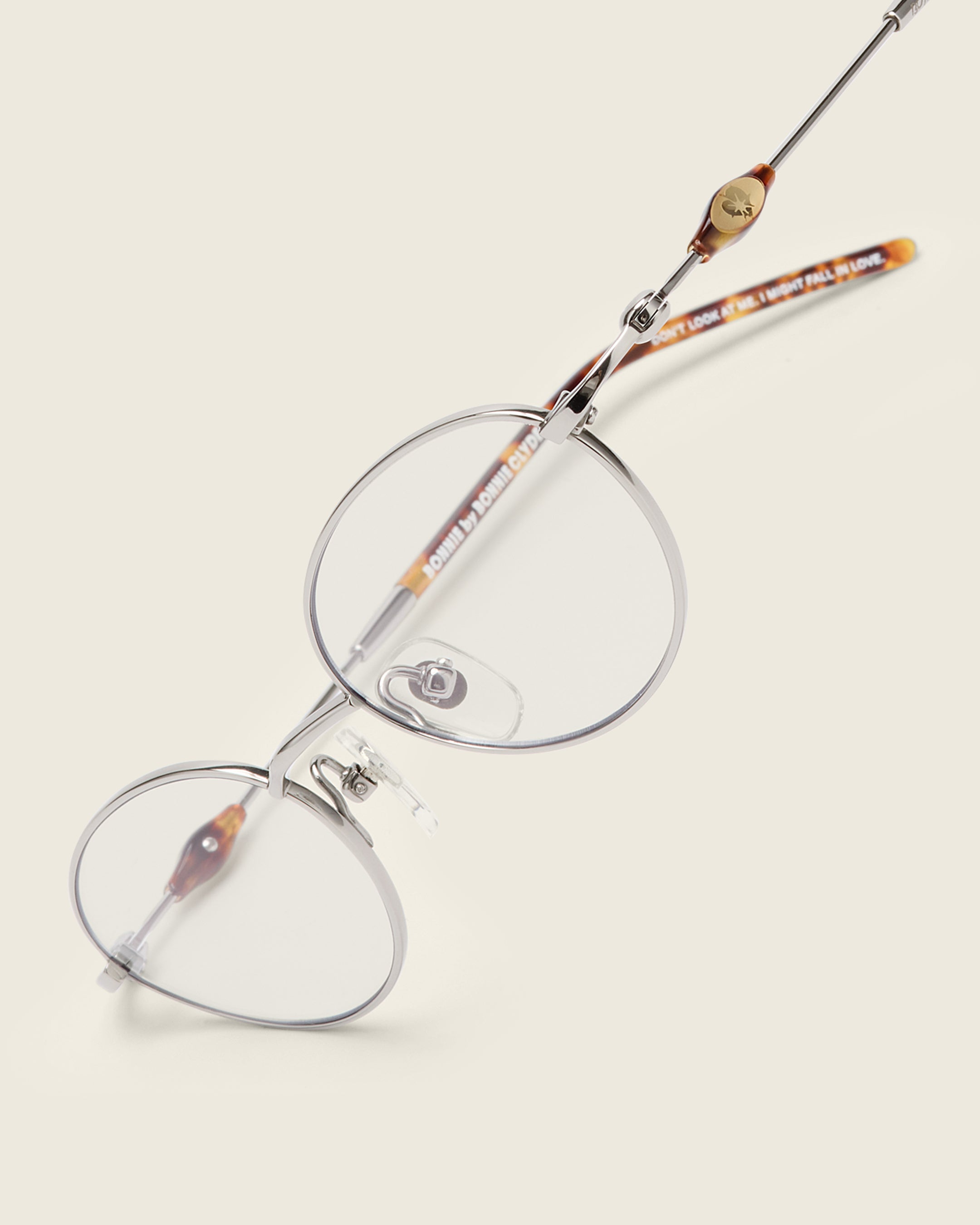 Slim, oval silver titanium frames with adjustable nose pads and lightweight acetate arm temple. Detail view.