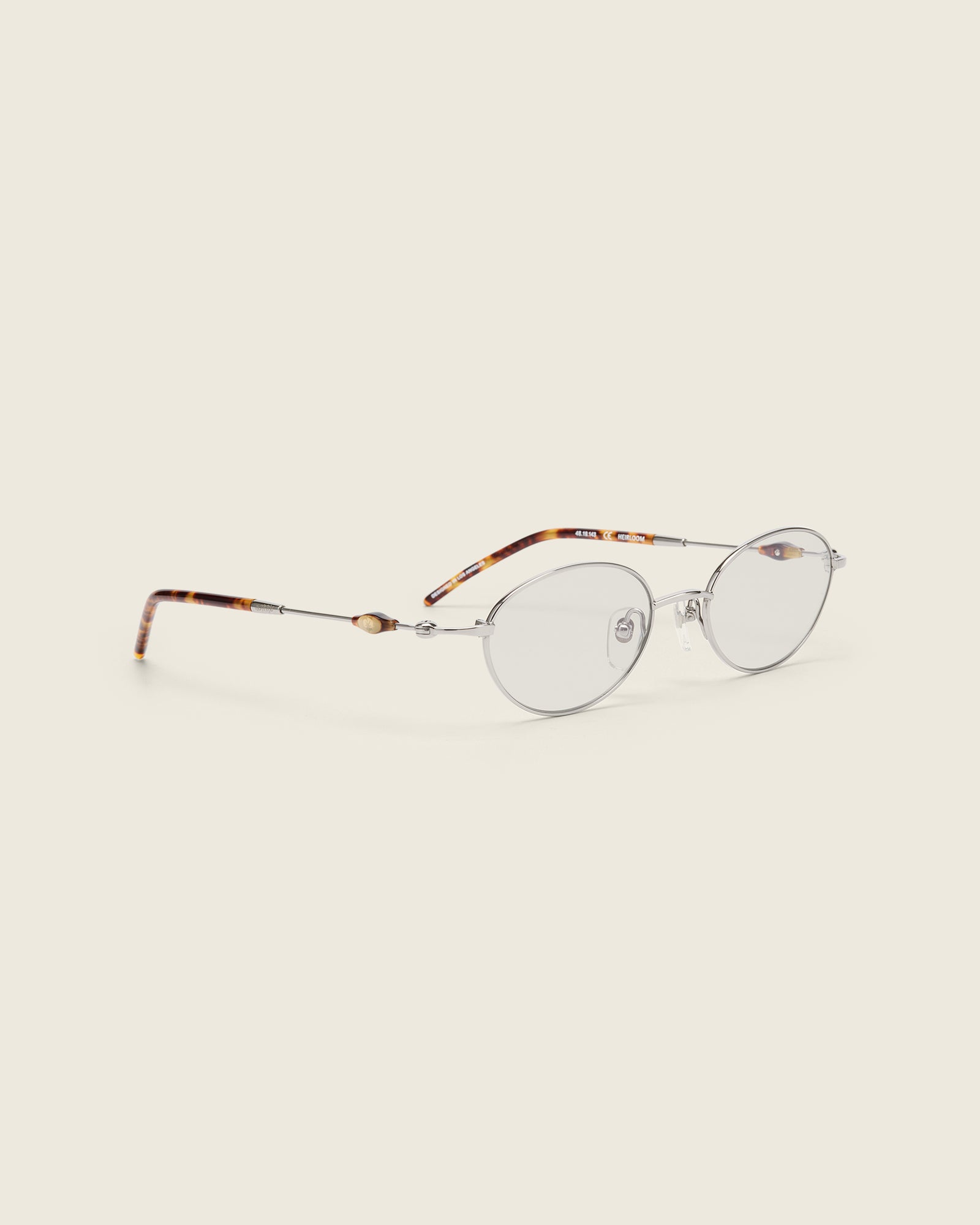 Slim, oval silver titanium frames with adjustable nose pads and lightweight acetate arm temple. Quarter view.