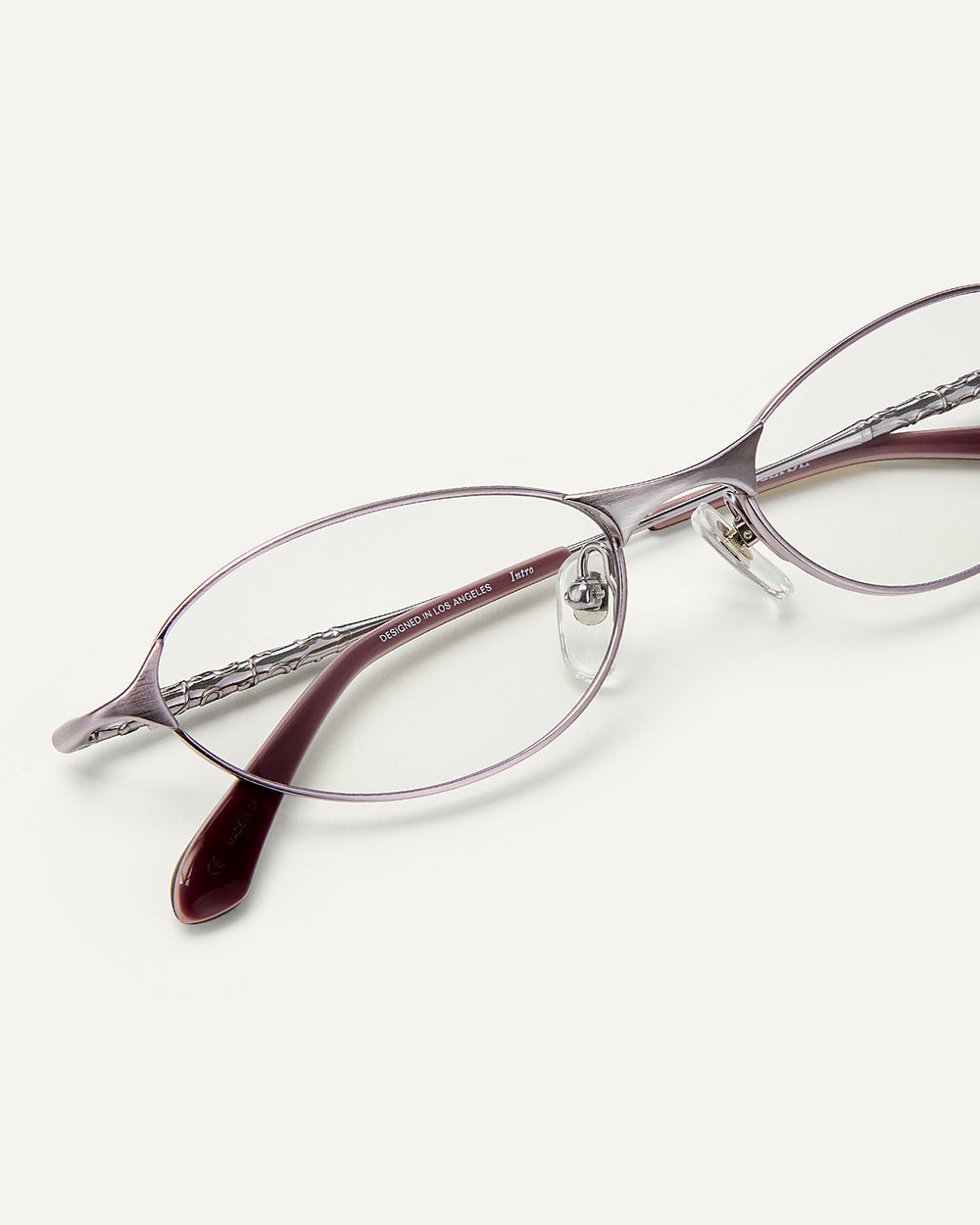 Close up shot of Bonnie Clyde Intro eyeglasses in purple titanium frames with dark purple acetate details and clear lenses.