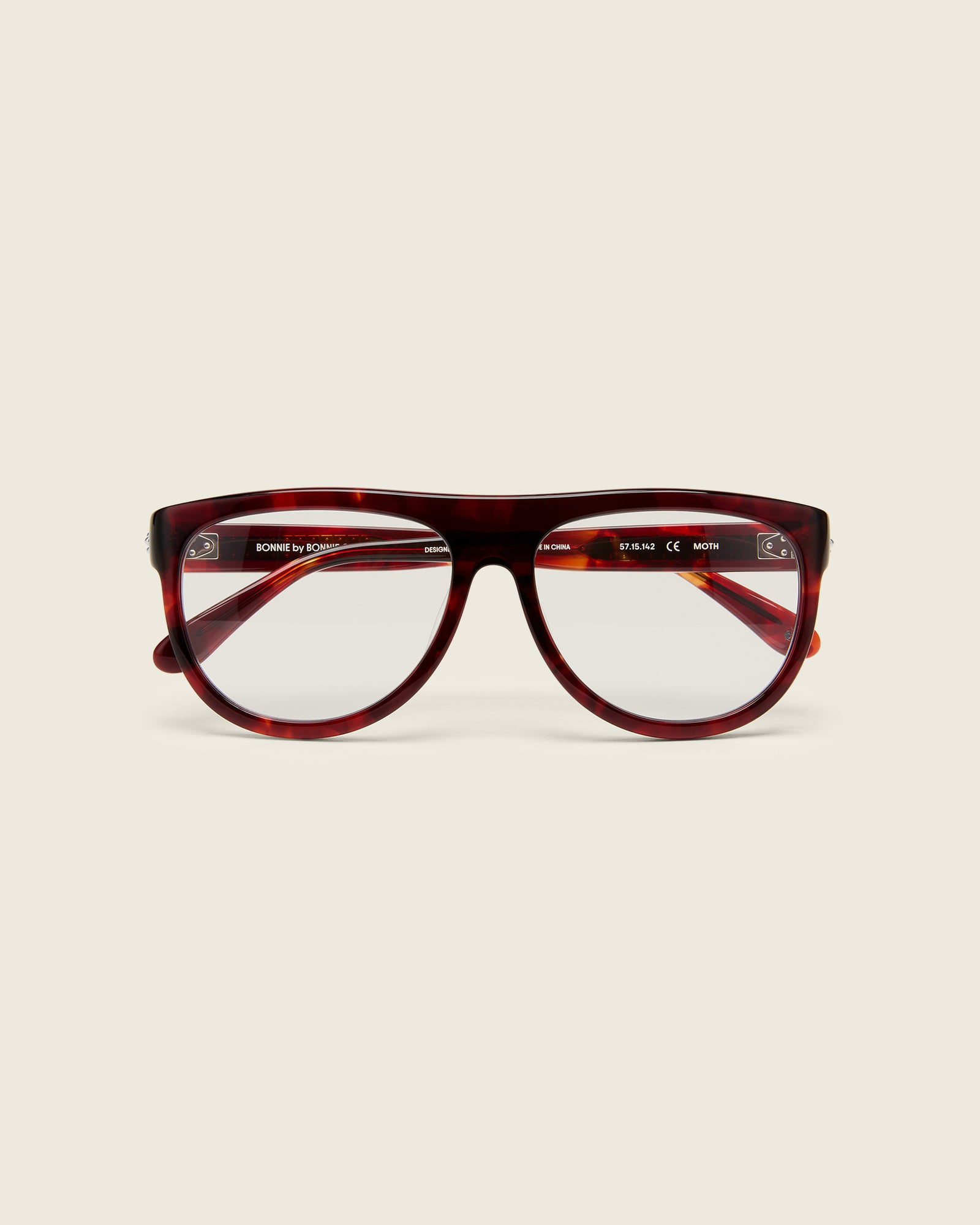 Oversized aviator-style red tortoise acetate frames with a bold browline and deep lenses on a cream background.