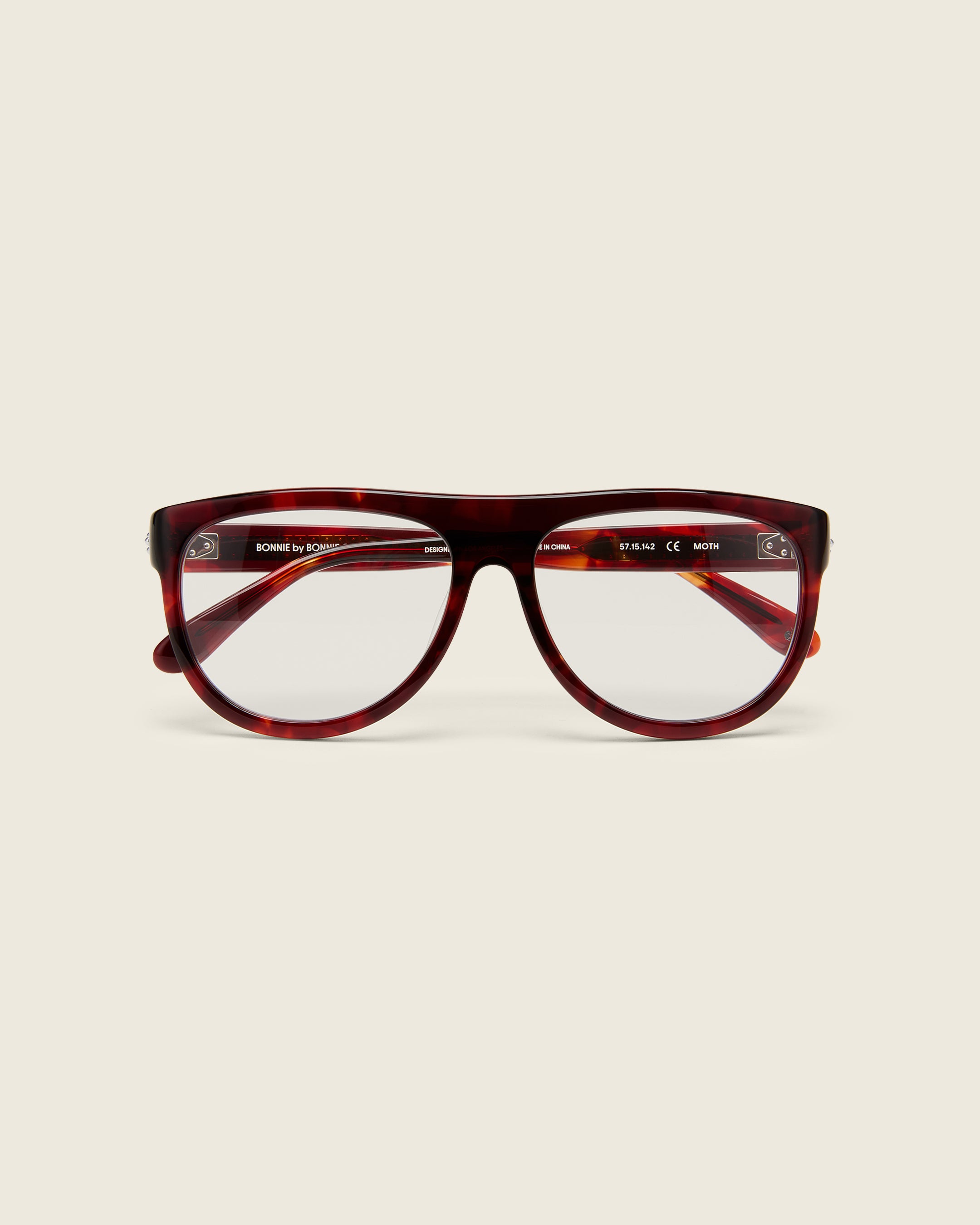 Oversized aviator-style red tortoise acetate frames with a bold browline and deep lenses on a cream background.