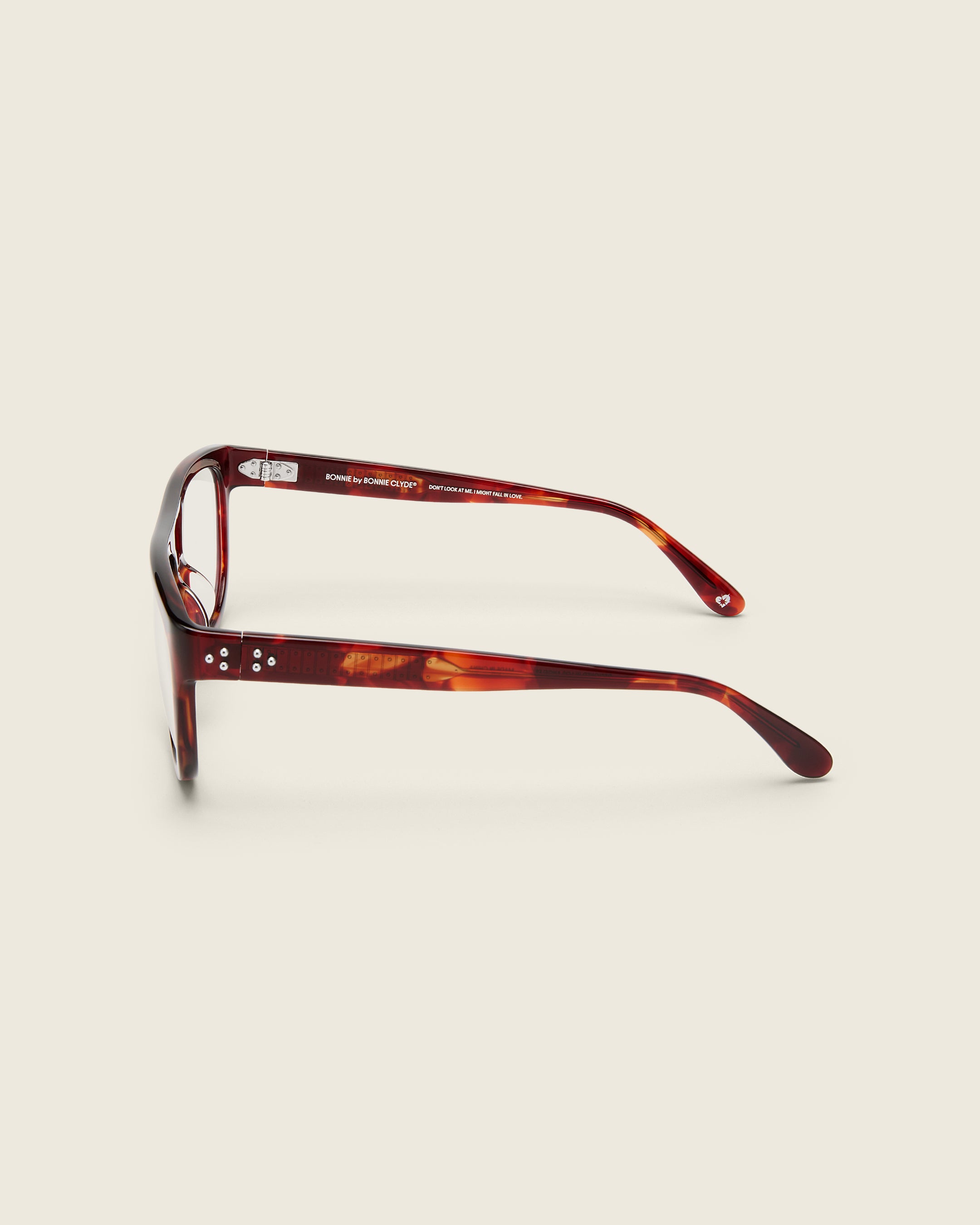 Oversized aviator-style red tortoise acetate frames with a bold browline and deep lenses on a cream background. Side view. Mirrored triple metal bead detailing on arm temples.
