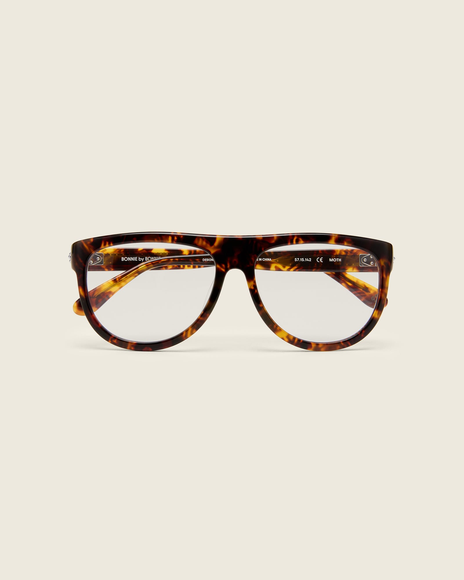 Oversized aviator-style tortoise acetate frames with a bold browline and deep lenses on a cream background. Face view. 