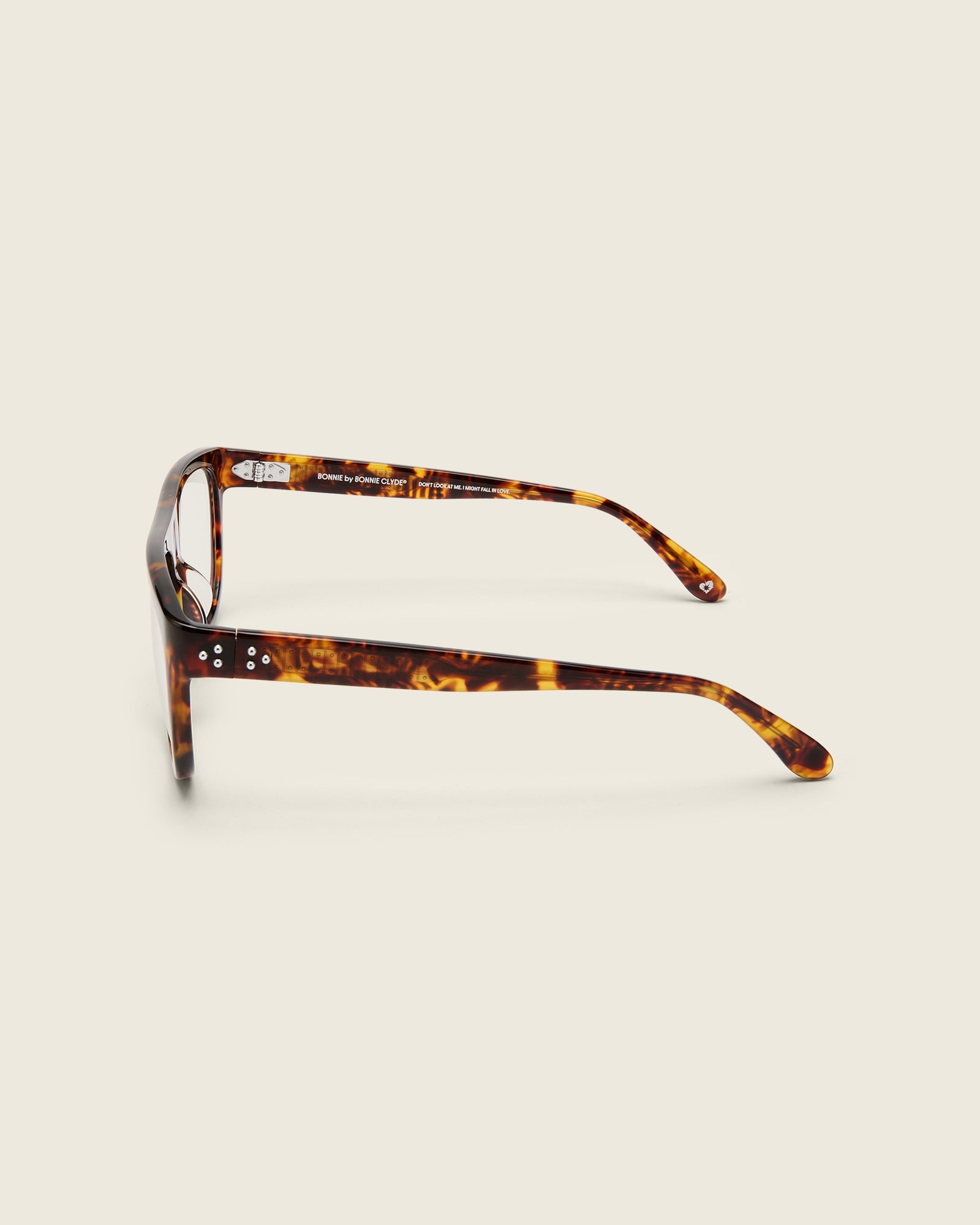 Oversized aviator-style tortoise acetate frames with a bold browline and deep lenses on a cream background. Side view. Mirrored triple metal bead detailing on hinge and arm temple.