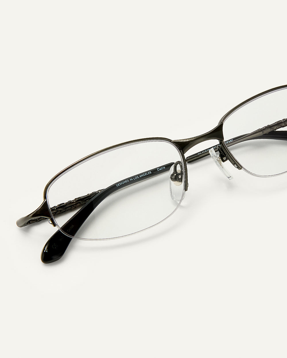 Close up shot of Bonnie Clyde Outro eyeglasses in gunmetal titanium frames with black acetate details and clear lenses.