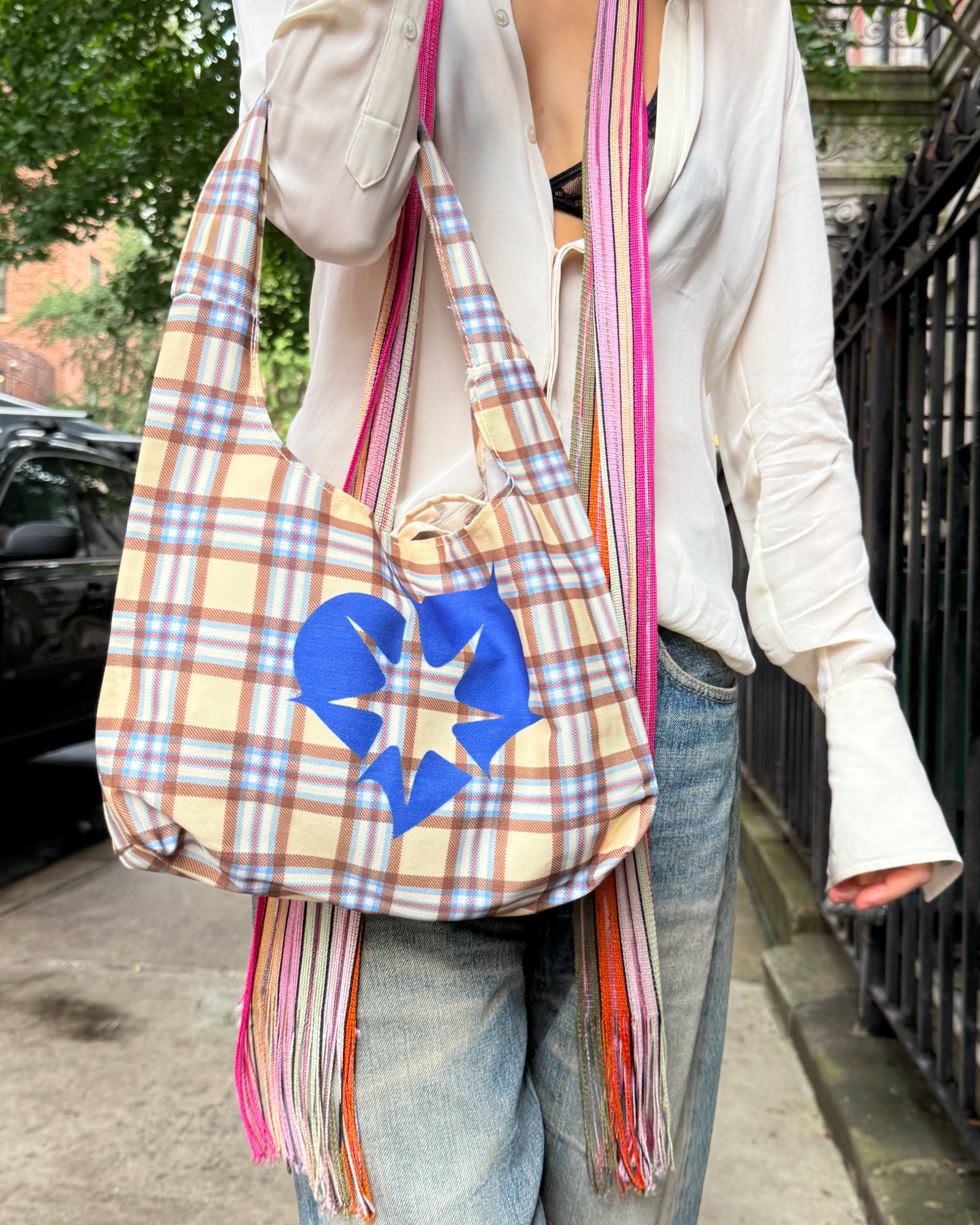 Person holding a Bonnie Clyde® plaid tote bag with blue heart design in New York City