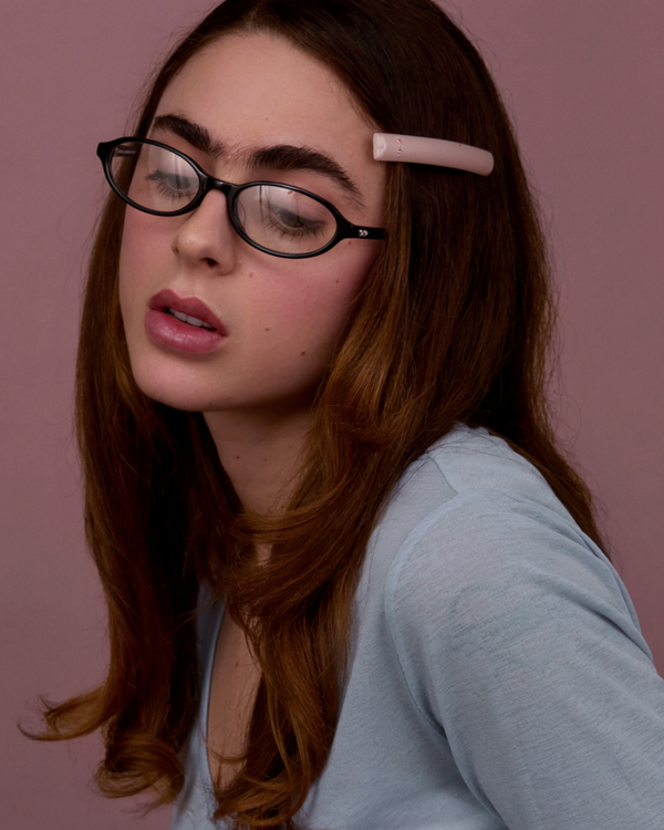 Bonnie Clyde Baby oval optical in black acetate with clear lenses and double heart detailing on the arms, styled on a model's face