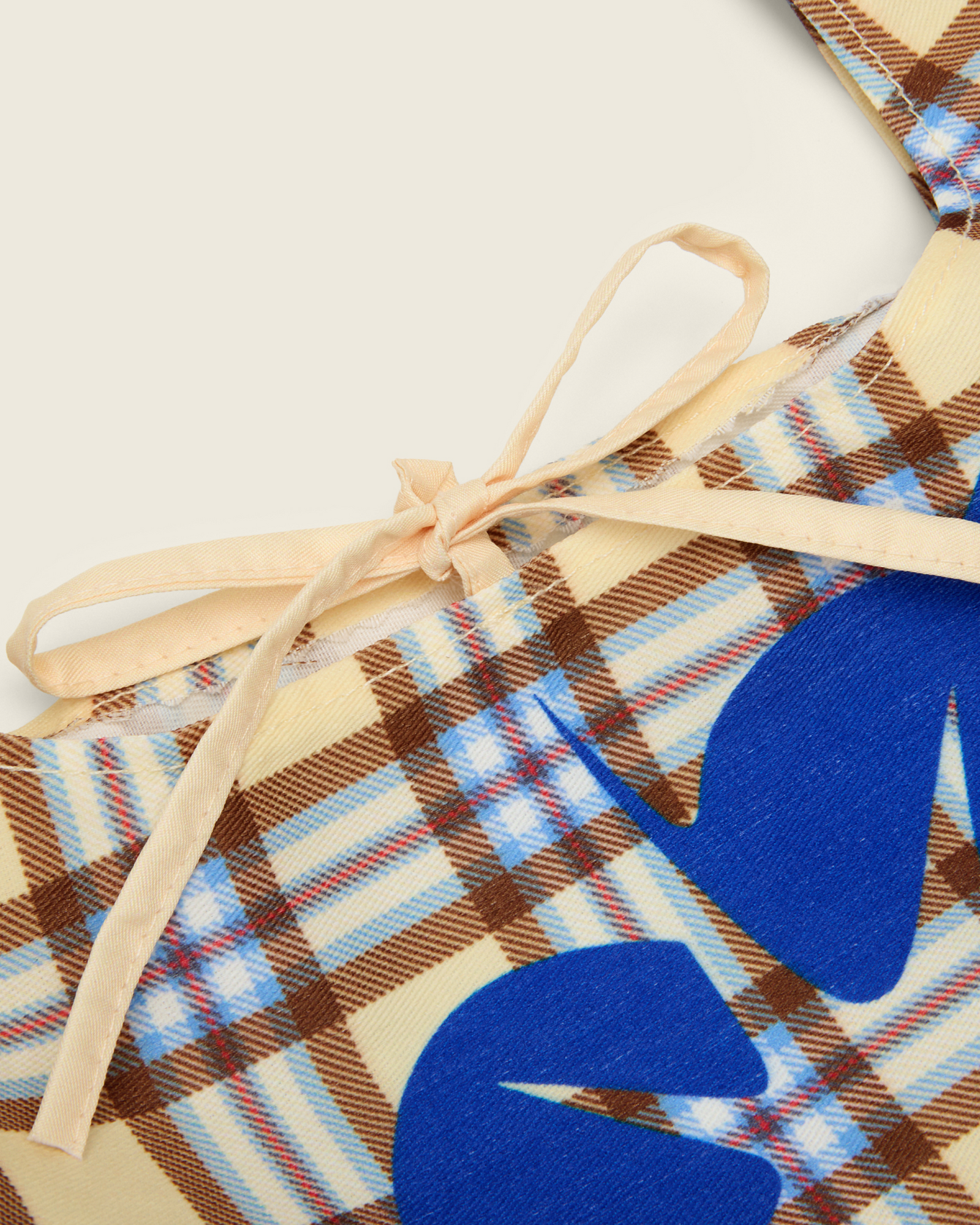 Bonnie Clyde® plaid tote bag with blue heart design on a beige background, detail shot